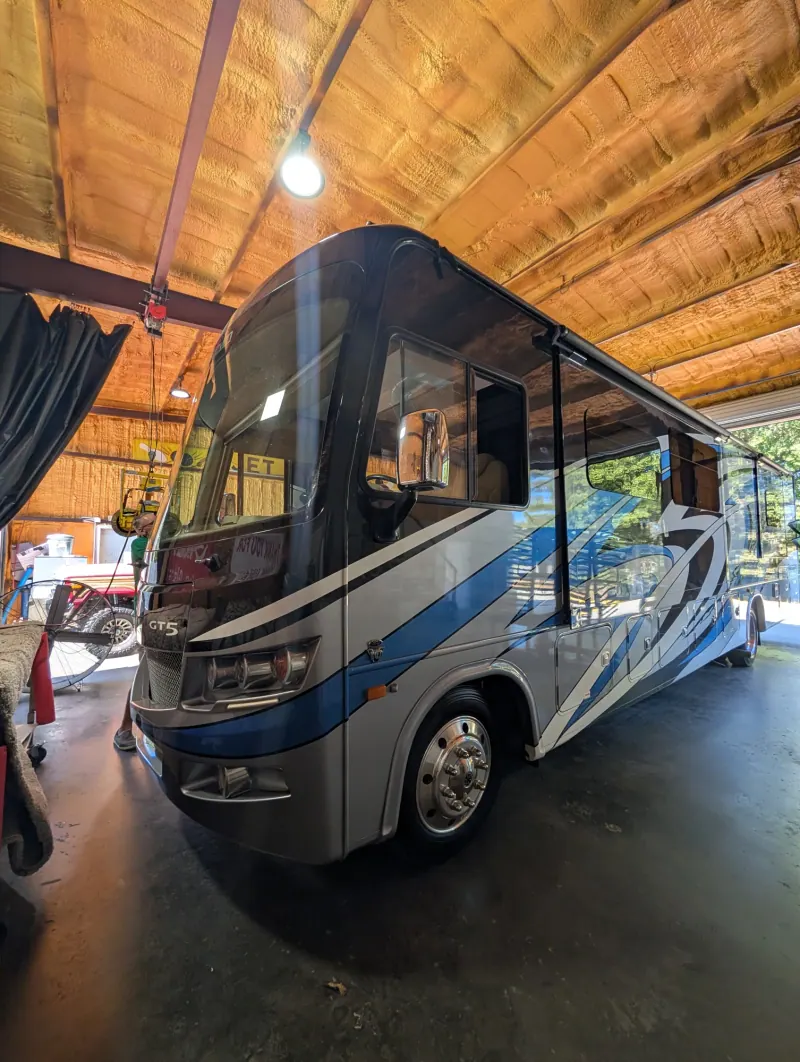 Blue and gray Class A motorhome in the Absolute Auto Glass service bay